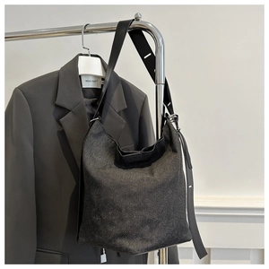 Detail der schwarzen Denim-Hobo-Tasche an einem minimalistischen Kleiderbügel aus Stahl