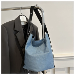 Detail der blauen Denim-Beuteltasche mit breitem schwarzen Riemen und Metall-Verstellschnalle