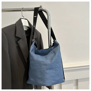 Detail einer blauen Denim-Beuteltasche mit schwarzem Gurt und natürlichen Falten