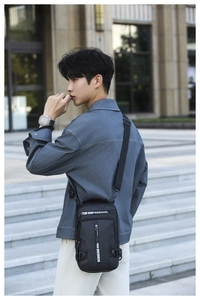 Detailed outdoor view of a black waterproof crossbody bag worn by a model in casual city style