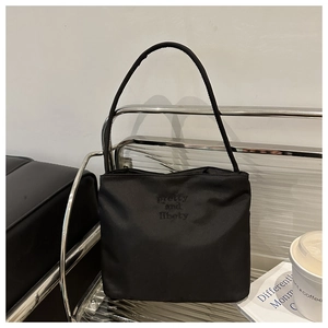 Detail of black nylon bucket bag with pretty and liberty embroidery on a modern metal shelf