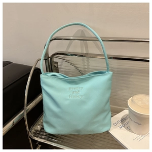 Close-up of light blue canvas tote bag featuring pretty and libety white embroidery
