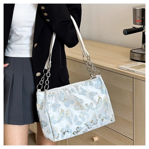 Detailed embroidery of blue and gold butterflies on a white tote bag with silver chain