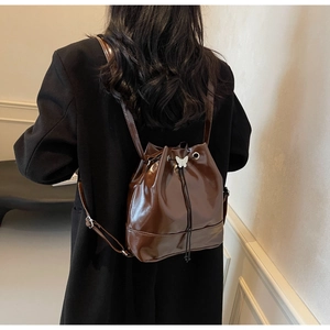 Détail d'un sac à dos seau marron foncé brillant avec décoration papillon blanc