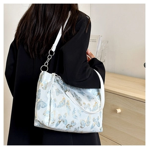 Detail of embroidered butterfly tote bag with white faux leather straps and silver rings