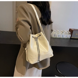 Close-up of cream bucket bag with glossy leather finish and silver butterfly charm
