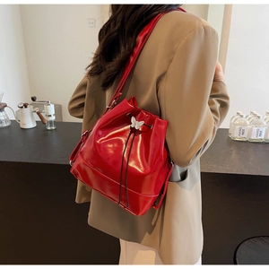 Detail of red glossy patent leather bucket bag with silver butterfly charm decoration
