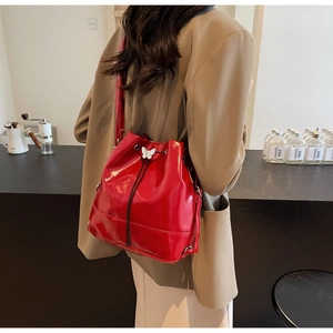 Detail of red bucket bag with drawstring closure and white butterfly metal buckle buckle