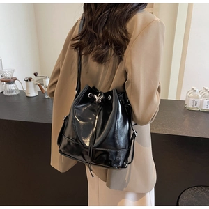 Détail d'un sac seau noir à cordon avec boucle papillon argentée sur une tenue de bureau