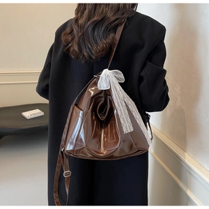 Sac à bandoulière en similicuir marron avec nœud en dentelle blanche sur modèle