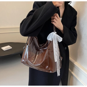 Détail du sac en cuir brillant marron foncé avec gaufrage 10 et nœud en dentelle blanche