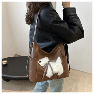 Dettaglio della borsa tote marrone con patch di cucciolo di peluche e fiocco a scacchi