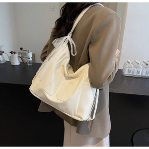 Detail of off-white oversized tote bag with numerical 10 embossing and lace bow detail