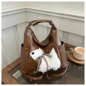 Dettaglio borsa marrone in ecopelle con un simpatico cucciolo di peluche 3D e fiocco