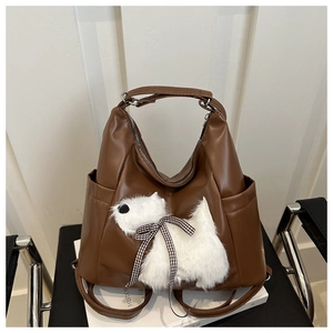 Dettaglio della borsa in pelle marrone con cucciolo di peluche e fiocco a scacchi