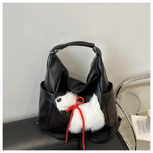 Dettaglio di una borsa hobo nera in ecopelle con un ciondolo a forma di cucciolo di peluche