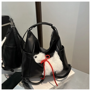 Dettaglio della borsa a spalla nera opaca con ciondolo a forma di cucciolo di peluche