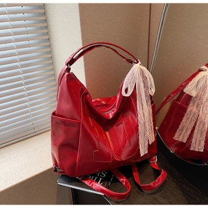 Détail du sac à main rouge brillant avec un nœud en dentelle blanche et écusson chiffre 10