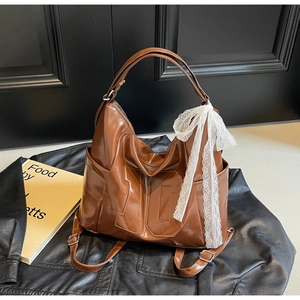 Détail d'un sac hobo marron avec le numéro 10 embossé et un ruban en dentelle blanche