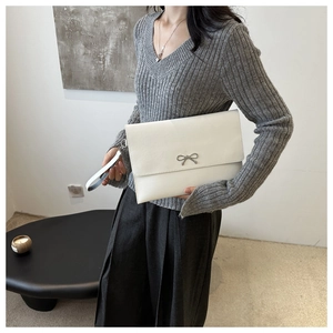 Detailansicht einer weißen Leder-Umschlagtasche mit Silberschleife und Handgelenkschlaufen