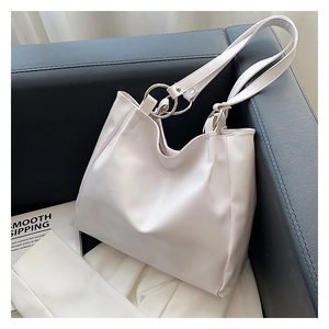 Detail of creamy white faux leather tote bag with large silver metal ring connector