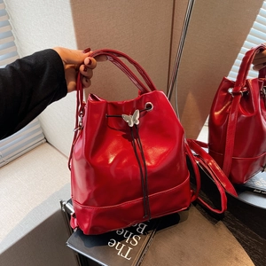 Sac à dos seau en cuir rouge brillant avec boucle papillon argentée et bretelles