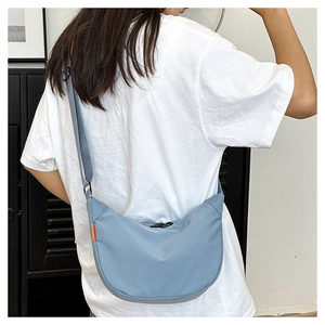 Detail of light blue crescent crossbody bag with black zipper and adjustable strap
