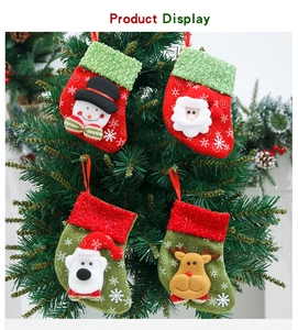 Detail of four Christmas stocking ornaments hanging on a pine tree with snowflakes