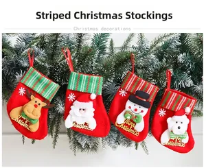 Detail of small Christmas stockings with 3D cartoon patterns hanging on a green tree