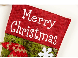 Detail of Christmas stocking fabric showing red burlap, green texture, and snowflake patch
