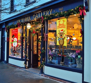 Outdoor Christmas hanging banners with snowman and reindeer designs at a shop entrance