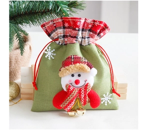 Detail van groene jute kerstcadeautas met pluche sneeuwpop en gouden kerstklokjes
