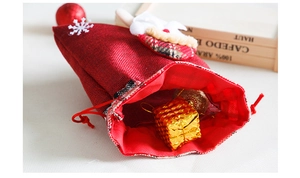 Detail van rode kerstcadeautas van jute met kerstman-applicatie en handig trekkoord