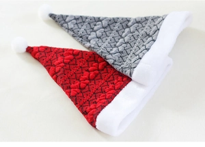 Detail of red and grey knitted Christmas hats featuring heart patterns and plush pom-poms