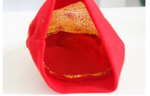 Dettaglio del tessuto rosso festivo con paillettes dorate per accessori di Natale