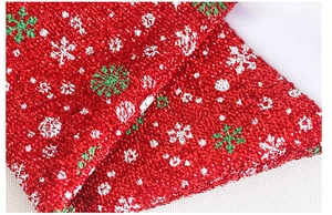 Dettaglio macro del tessuto glitterato rosso con fiocchi di neve per decoro natalizio