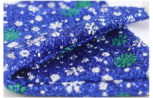 Dettaglio macro di tessuto blu glitterato con motivi a fiocchi di neve colorati