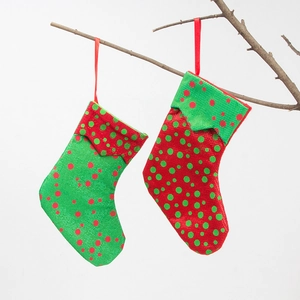 Christmas stocking gift bags in red and green with polka dots on a hanging branch