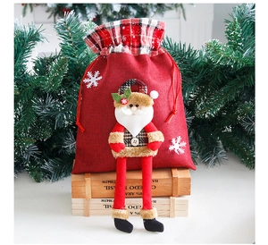 Detail of red linen Christmas gift bag with 3D Santa plush and drawstring closure