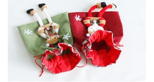 Detail view of linen Christmas drawstring gift bags with plush snowman and Santa motifs