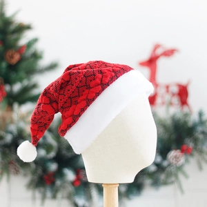 Knitted Christmas hat with red and black pattern and soft white plush pompom on a stand