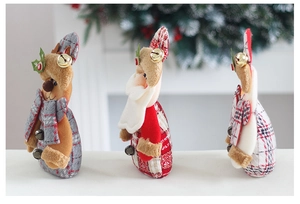 Detailed view of three plush Christmas dolls with grey and red plaid fabric and golden bells