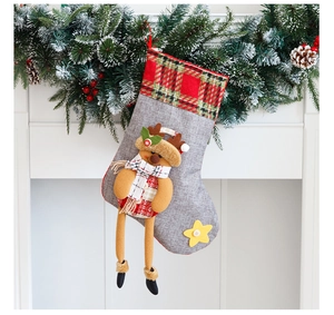 Détail d'une chaussette de Noël en toile avec poupée renne suspendue à une cheminée blanche