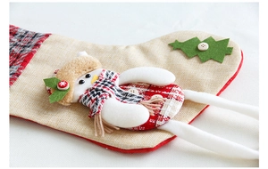Gros plan détaillé d'une chaussette de Noël en jute avec pingouin en peluche et écharpe à carreaux