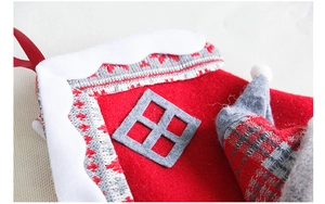 Detail van een kerstsok gemaakt van rood vilt en grijs breiwerk met huisontwerp