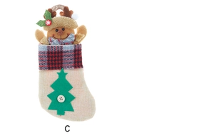 Close-up of linen Christmas stocking with reindeer plush and green tree patch detail