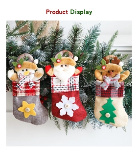 Detail of burlap Christmas stockings with snowman, Santa, and reindeer hanging on pine branches
