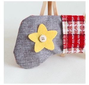 Detail of small burlap Christmas stocking with red plaid cuff and felt star with button