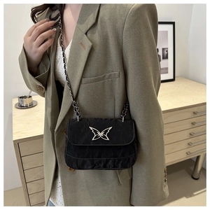 Detail of black crossbody bag with silver butterfly metal logo and leather chain strap