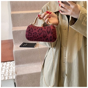 Close-up of leopard print evening bag with golden metal handle and chain strap